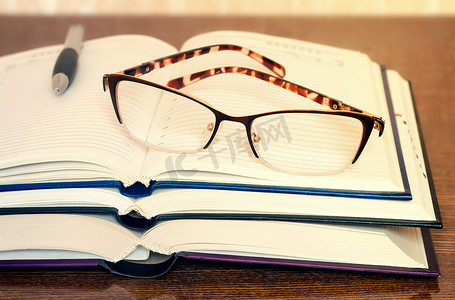 桌面上的眼镜、书籍和笔记本。