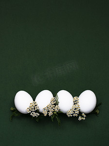 小花装饰摄影照片_节日复活节彩蛋，绿色背景上有白色小花。
