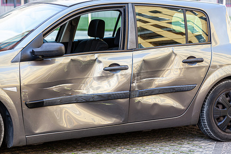 凹痕摄影照片_损坏的汽车，门上有划痕和凹痕，交通事故后汽车上有凹痕，