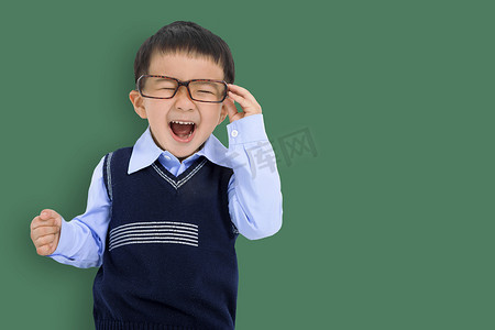 快乐的小男孩拿着眼镜，站在黑板前玩得开心