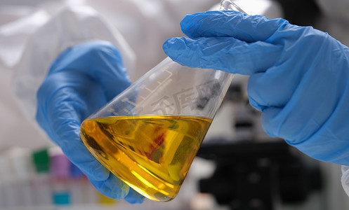 手绘科学家在化学实验室拿着带有金油液体的实验室玻璃器皿