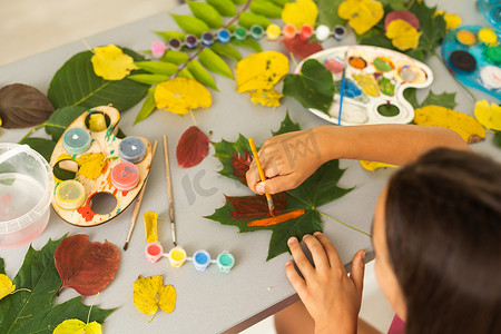 会员diy摄影照片_孩子用颜料画树叶，画一幅画，制作树叶的版画。