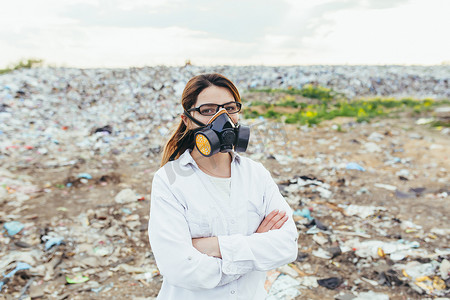 环境污染小报摄影照片_垃圾填埋场戴着防护呼吸面罩的女科学家评估环境污染程度