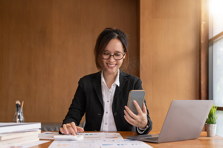 亚洲女性拿着智能手机，同时使用计算器进行商业财务会计计算货币银行贷款租金管理费用财务税收做文书工作概念，特写。