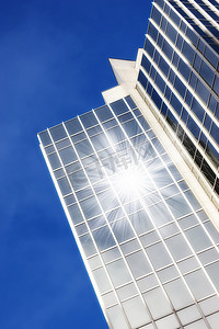 几何城市摄影照片_摩天大楼上的几何玻璃窗，阳光从下面反射着蓝天背景的镜头耀斑。