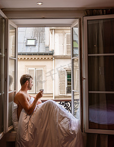 年轻人坐在窗前，眺望巴黎这座城市。
