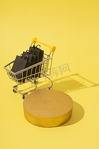 星期五黄色摄影照片_模型讲台或基座以及带购物袋的微型超市推车，黑色星期五销售黄色
