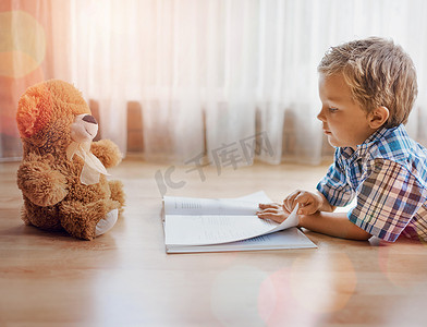 我想告诉你一个故事......拍摄的是一个小男孩躺在地板上，手里拿着一本书和他的泰迪熊。