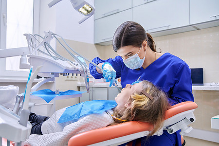 女医生牙医使用麻醉剂为小女孩治疗牙齿。