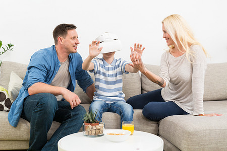 幸福的家庭在客厅沙发上享受使用虚拟现实耳机玩游戏的乐趣