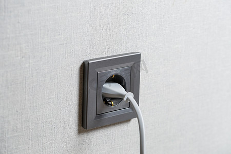 墙上有一个灰色插座，其中包括一个带有白色电线的设备。