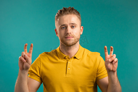 英俊的男人用手和两个手指展示空气引用手势，弯曲手指隔离在蓝色背景上。