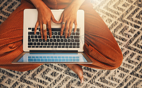 上图是未知的混血女性在家里的客厅里使用笔记本电脑写博客。