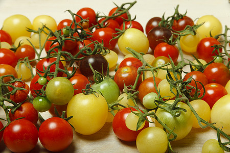 白桌上的小红、黄、绿和黑樱桃番茄，自然背景，图案。