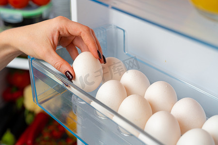 天然凉爽摄影照片_女手从冰箱里拿鸡蛋