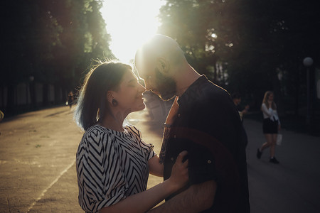 拥抱恩爱摄影照片_一对恩爱的情侣在夏日阳光的背景下拥抱并看着对方的眼睛