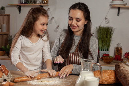 妈妈和她的女儿正在厨房烤面包，玩得很开心。