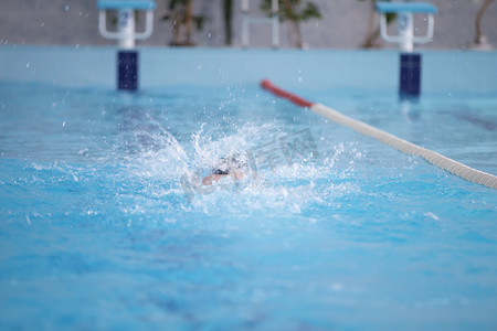 飞溅水花摄影照片_一名运动员正在运动池里游泳。