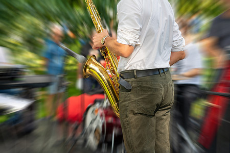 萨克斯管吹奏者在街头节日表演期间演奏动态背景模糊的萨克斯管