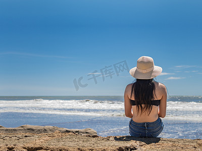 戴帽子的女人从背对大海，戴帽子的女孩望向大海，度假概念，一个女孩看海的后视图