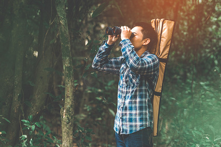 遇见你预见爱摄影照片_在森林里用双筒望远镜寻找目的地的人是失踪的人或可预见的未来。