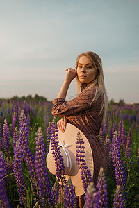 漫步摄影照片_一位戴着草帽的美丽女子走在开满紫色花朵的田野里。