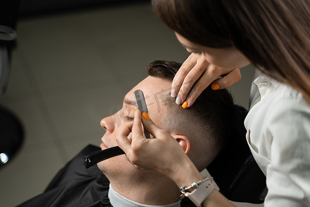 直剃刀在理发店给男人剪头发。