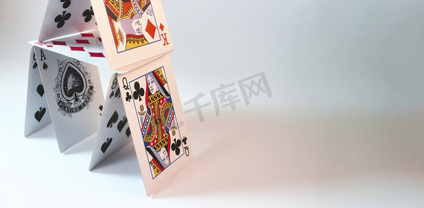卡扑克牌通摄影照片_白色背景下堆放扑克牌的房子，有文字放置的空间