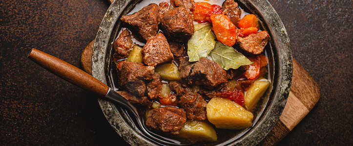 质朴金属锅顶视图中炖肉、蔬菜和肉汁的宏观特写