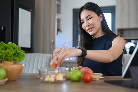 健康的年轻女性在厨房里用新鲜蔬菜和水果制作素食餐。