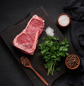 黑色的板摄影照片_新鲜的生牛肉，黑色背景的西冷牛排，顶视图。