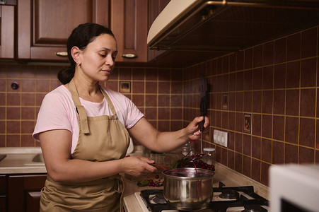 多民族妇女，家庭主妇在家厨房煮樱桃果酱