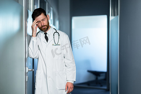 疲惫的医生工作过度，头痛严重，感觉不好，诊所走廊里的一个男人对结果感到失望