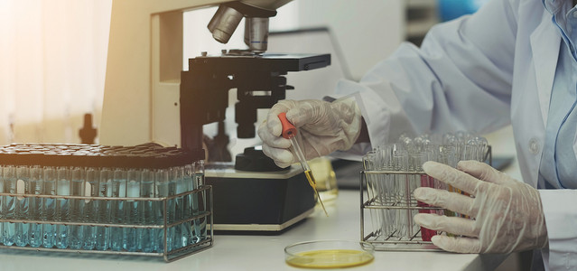 特写生物化学实验室研究，化学家正在实验室用显微镜设备和含有化学液体的科学实验玻璃器皿分析样品。