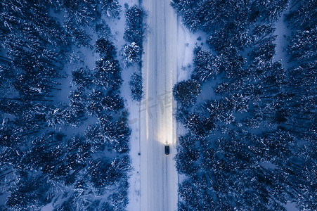 雪佛兰汽车促销摄影照片_雪路与汽车、冬季森林的鸟瞰图