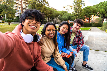 一群多种族大学生朋友在外面用手机自拍。