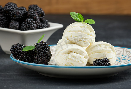 白色冰淇淋球摄影照片_圆盘里放三勺白色冰淇淋，黑桌上放着薄荷叶