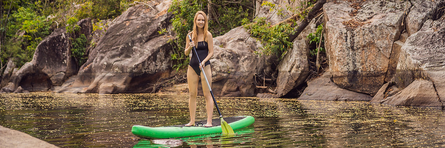 SUP 站起来桨板女人在湖上桨板快乐地站在蓝色水面上的桨板上。