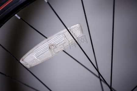 自行车黑色车轮的灰色金属辐条上的一个塑料白色反光镜