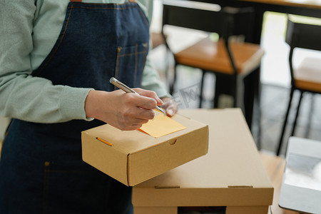 在线购物，初创小企业主在工作场所的纸板箱上写下地址。