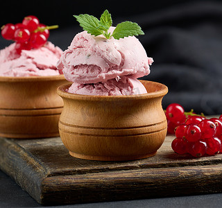 球冰淇淋摄影照片_黑色桌子上放着粉红色的冰棒和红醋栗。