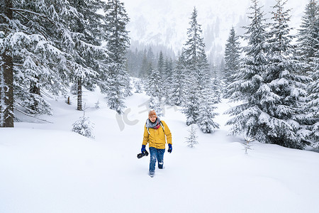 摄影师正在冬季山林的雪堆中行走