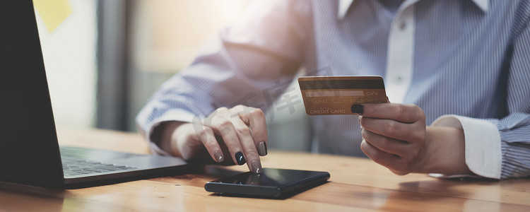 手持信用卡并使用移动智能手机与早晨，网上购物。