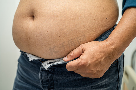 肥胖女性摄影照片_超重的亚洲女性在办公室展示肥胖的腹部。