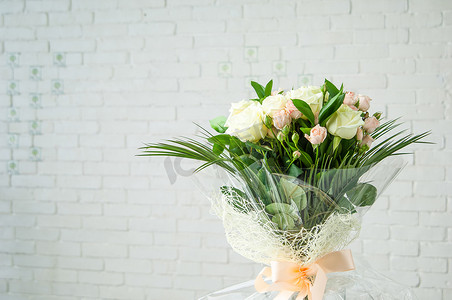 美丽的花束，配有鲜香的白玫瑰和白墙上的装饰草