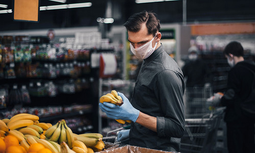 家电卖场开业摄影照片_戴防护手套的顾客在超市挑选香蕉
