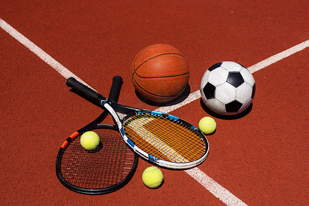 一组黑色背景的运动器材，包括网球、篮球、足球和拳击器材，背景有复制空间