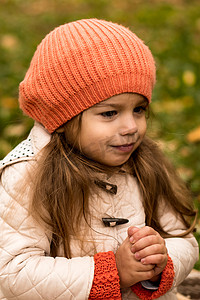 肖像小学龄前小女孩在橙色贝雷帽在黄色落叶在篮子里裹着毯子梦幻般地看着别处。