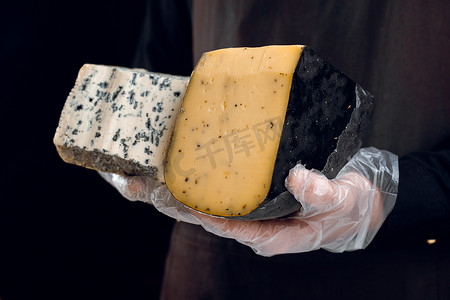 蓝色布纹摄影照片_蓝纹奶酪和豪达，手中有意大利香草。