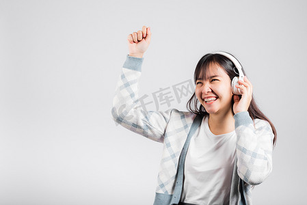 女人兴奋地笑着用蓝牙耳机听音乐广播，用智能手机跳舞